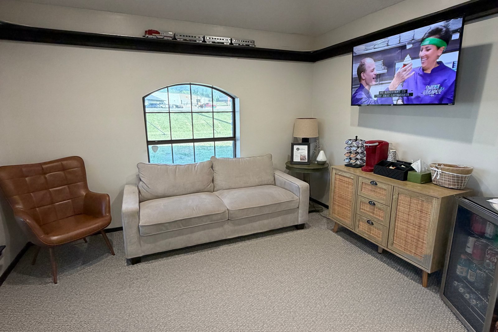 The Old Betsy Dental of Joshua waiting area — a plush sofa, a leather accent chair, and a coffee and refreshment station